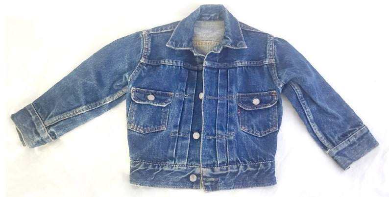 May include: A vintage blue denim jacket with a button closure, two chest pockets, and long sleeves.