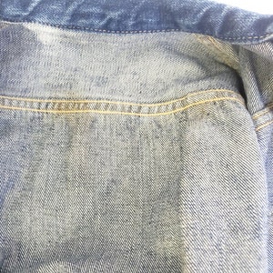 May include: Close-up of the inside of a denim jacket, showing the light blue denim fabric and the yellow stitching along the seams.