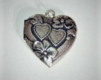 May include: Silver heart-shaped locket with an intricate design of two hearts and flowers.