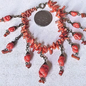 May include: A coral bracelet with a silver chain and multiple coral charms. The bracelet is made of small, irregular pieces of coral, and the charms are shaped like small coral flowers.