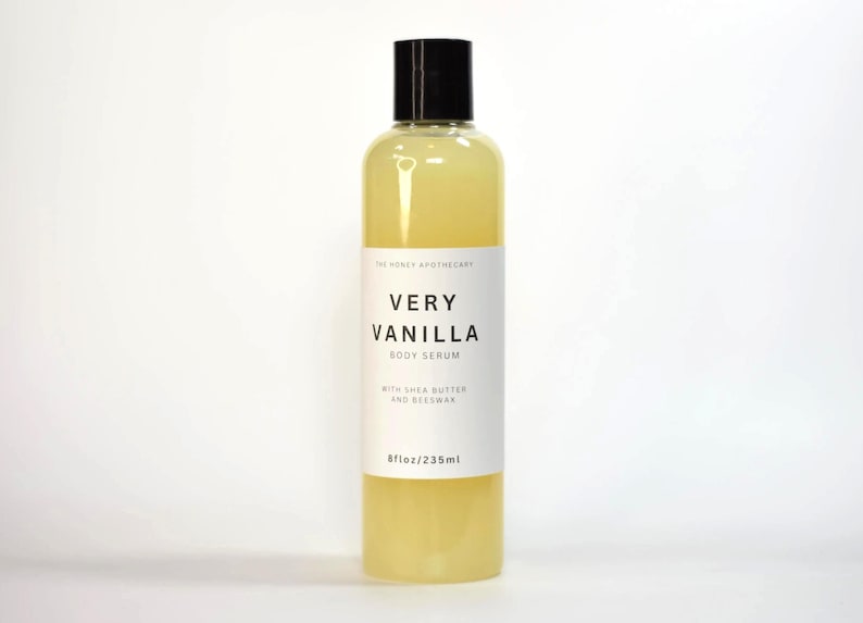 May include: A clear bottle of Very Vanilla Body Serum with a black cap. The label reads "Very Vanilla Body Serum" with the ingredients "with Shea Butter and Beeswax". The bottle contains 8 fl oz / 235ml of serum.