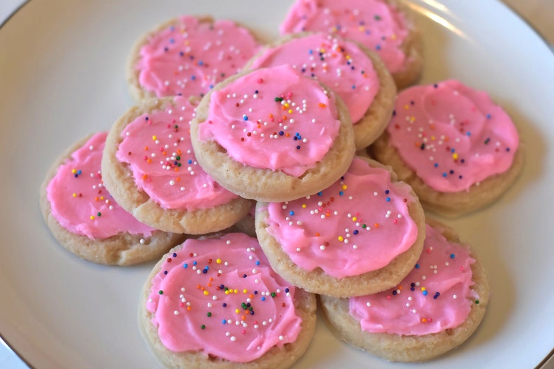 May include: A plate of pink frosted sugar cookies with colorful sprinkles on top.