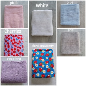 Op de afbeelding: Assortiment van 10 verschillende stofstalen in verschillende kleuren en patronen, waaronder roze, wit, blauw, grijs, kersen, bloeiende aardbei en paarse bloemen.