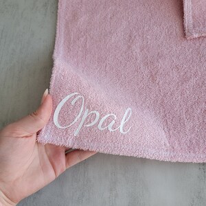 Op de afbeelding: Een roze handdoek met de naam "Opal" geborduurd in wit.