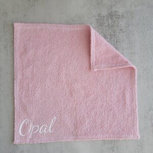 Op de afbeelding: Een roze handdoek met de naam "Opal" geborduurd in wit.