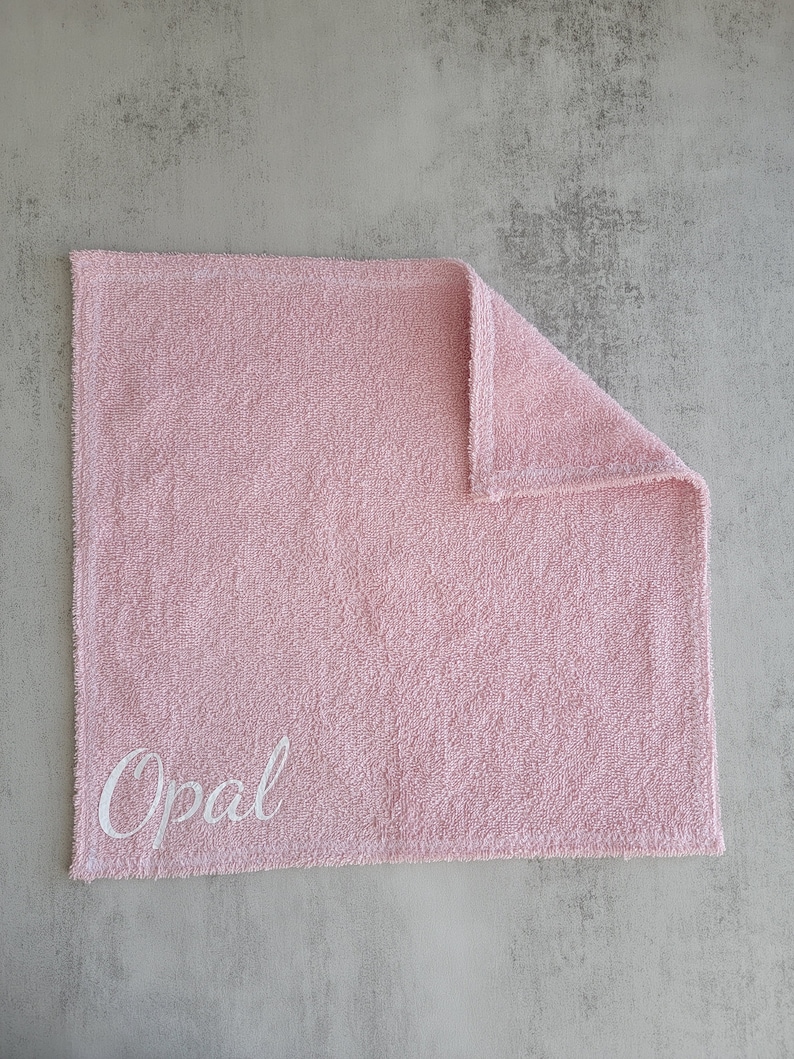 Op de afbeelding: Een roze handdoek met de naam "Opal" geborduurd in wit.