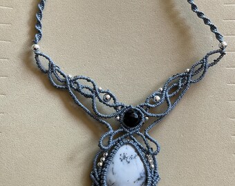 May include: A gray macrame necklace with a white and black agate pendant and silver beads.