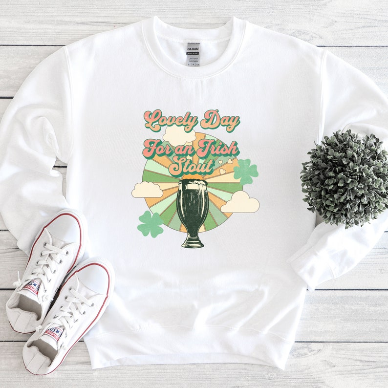 May include: White sweatshirt with a retro-style graphic design featuring a glass of dark beer and the text "Lovely Day for an Irish Stout".