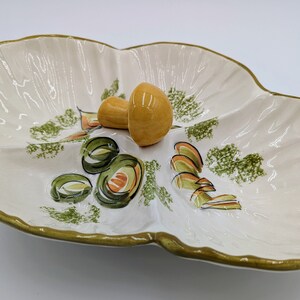 May include: A white ceramic serving dish with a green and orange mushroom design. The dish has three sections and a scalloped edge.