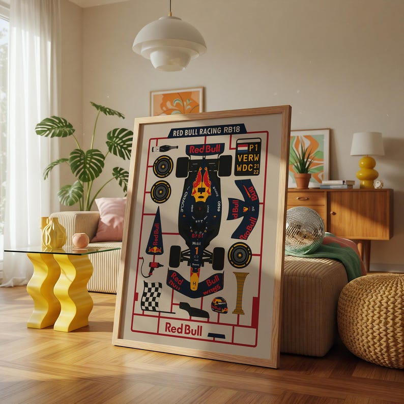 May include: Framed Red Bull Racing RB18 poster. The poster features a schematic design of a Formula 1 car with the Red Bull logo and text. The color scheme includes red, blue, and yellow accents. The poster is displayed in a well-lit living room setting.
