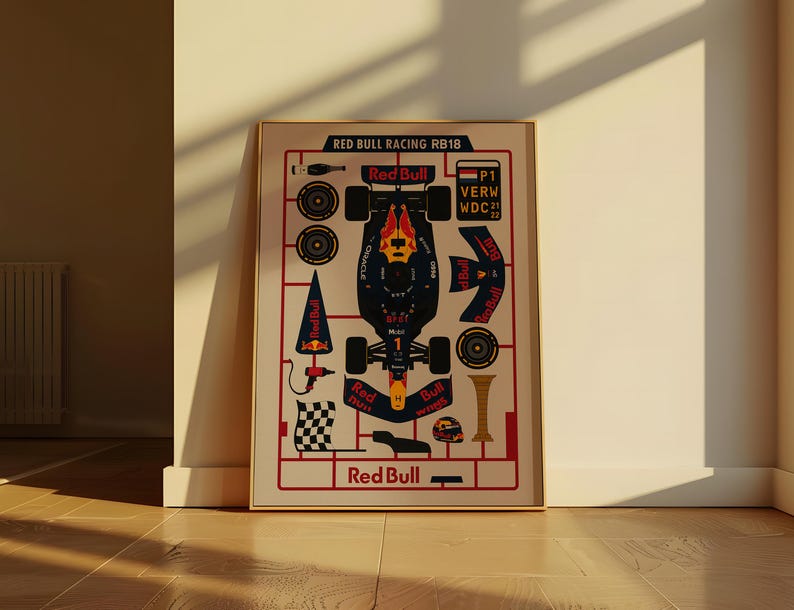 May include: Framed poster featuring a schematic of a Red Bull Racing RB18 Formula 1 car. The design includes car components, text, and the Red Bull logo. The poster is in a gold frame and leans against a wall.