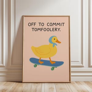 May include: A framed art print featuring a yellow duck wearing a blue headscarf, riding a blue skateboard with green wheels. The text "OFF TO COMMIT TOMFOOLERY" is above the duck on a pink background.