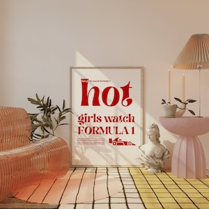 May include: A white framed poster with red text that reads "hot girls watch formula 1". The poster is hanging on a wall in a room with a pink and yellow checkered floor. There is a pink side table with a potted plant and a white bust sculpture on the table.