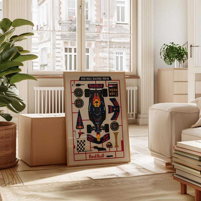 May include: A framed print featuring a schematic of a Red Bull Racing RB18 Formula 1 car. The print includes the car's components, logos, and text, with a color scheme of red, navy, and yellow. The print is displayed in a light-colored wooden frame.