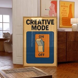 Może przedstawiać: Oprawiony plakat z napisem "CREATIVE MODE" nad niebieskim prostokątem z pomarańczowym przełącznikiem z napisami "ON" i "OFF". Widoczne są dwa inne oprawione plakaty, jeden z osobą palącą, a drugi z kciukiem w górę.