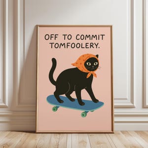 May include: Framed art print showing a black cat on a blue skateboard, wearing an orange headscarf. The print has the text "OFF TO COMMIT TOMFOOLERY" in black. The background is a light pink colour.