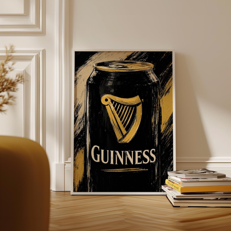 May include: A framed art print featuring a black Guinness can design with a gold harp logo and the Guinness text in white. The background has gold brushstrokes. The print is displayed on a wooden floor.
