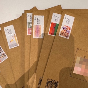 May include: Several brown paper envelopes with postage stamps attached. The stamps display diverse designs and colours. Some envelopes are stamped with "SANTA MAIL". The stamps are marked "Eire" and "EUR2.65".