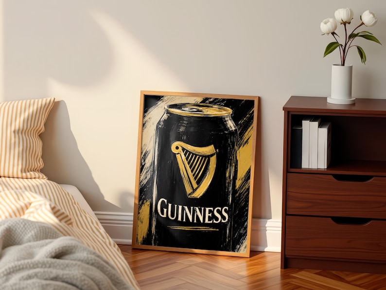 May include: A framed art print featuring a stylized depiction of a Guinness can. The artwork showcases a black can with a gold harp logo and the word "Guinness" in white. The background has gold and black brushstrokes.