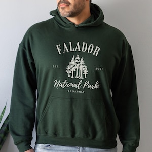 May include: A dark green hooded sweatshirt with a white graphic print that says "Falador National Park Est 2001 Asgarnia".