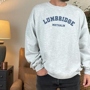 May include: A gray sweatshirt with a blue and white graphic print that says "Lumbridge Misthalin".