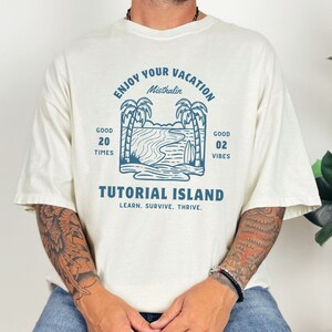May include: A white t-shirt with a blue graphic design of palm trees, a beach scene, and the text "Enjoy Your Vacation Misthalin Good 20 Times Good 02 Vibes Tutorial Island Learn. Survive. Thrive."