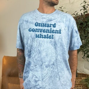 May include: A light blue tie-dye t-shirt with the text "Onward convenient whale!" printed in blue.