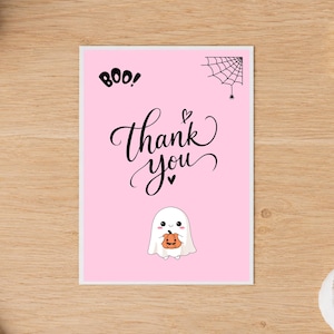May include: A rectangular greeting card with a light pink background featuring the black text BOO! and thank you in cursive script. A black spider web with a small spider is in the top right corner, and a white ghost holding a pumpkin is at the bottom.