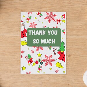 May include: A rectangular greeting card with a white background featuring a repeating pattern of Santa Claus figures, red snowflakes, yellow stars, and Christmas ornaments. A green rectangular box in the center displays the text THANK YOU SO MUCH.