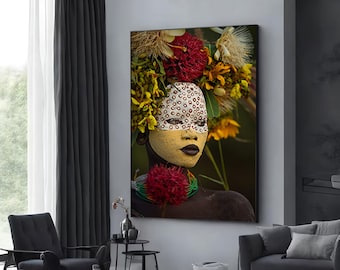 May include: A portrait of a person with dark skin wearing a headdress of colorful flowers and a white face paint with black dots. The person is looking directly at the camera.