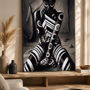 May include: A framed black and white wall art print featuring a person with dark skin adorned in intricate white body paint patterns, including circular motifs, diagonal stripes, and geometric shapes, captured in a seated, forward-facing pose.