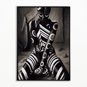May include: A black and white photographic print featuring a figure adorned with bold, high-contrast patterns. The design includes circular motifs, thick diagonal stripes, and intricate markings across the skin, presented in a vertical frame.