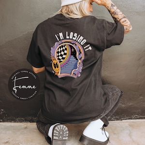 May include: Black t-shirt with a graphic of a head with a psychedelic design and the text "I'm Losing It".