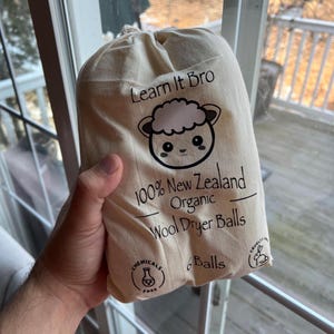 Peut inclure: Un sac en coton blanc avec un motif de mouton de dessin anim&eacute; noir et blanc. Le sac contient 6 boules de s&eacute;chage en laine. Le sac porte l'inscription "Learn It Bro" et "100% laine de s&eacute;chage en laine biologique de Nouvelle-Z&eacute;lande" imprim&eacute;e dessus.