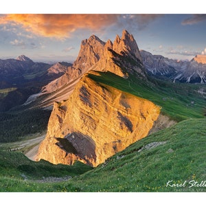 Puede incluir: Una vista panorámica de una cordillera al atardecer. Las montañas son rocosas y escarpadas, con un brillo dorado en las cumbres. El cielo es una mezcla de azul, rosa y naranja.