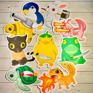 Peut inclure: Un ensemble de neuf autocollants color&eacute;s repr&eacute;sentant diff&eacute;rents animaux avec des armes et des accessoires uniques. Les autocollants comprennent une tortue avec un canon, un pingouin avec un couteau, un lapin avec un marteau, un axolotl avec des yeux laser, un chat avec une &eacute;p&eacute;e, un canard avec un couteau, une grenouille avec un katana, un gecko avec du feu et une tortue avec une fus&eacute;e.
