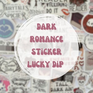 May include: A selection of stickers with a dark romance theme. The stickers feature text such as "Dark Romance Reader" and "Villains". The central sticker reads "Dark Romance Sticker Lucky Dip" in a pink font, within a white circle.