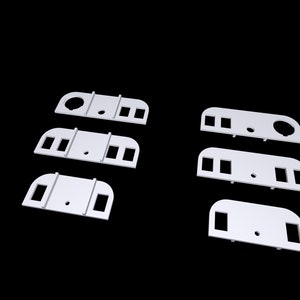 May include: Six white plastic wall mount brackets with different hole configurations.