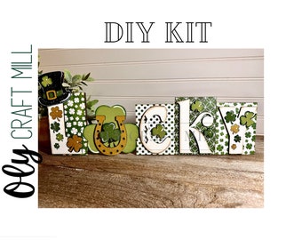 May include: DIY kit for a "Lucky" sign with green shamrock and horseshoe decorations. The sign is made of wood and is painted white with green and gold accents.