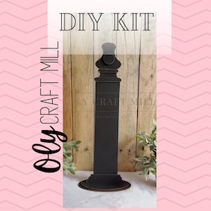 May include: DIY kit for a black wooden sign with a decorative finial. The sign is labeled "Olly Craft Mill".