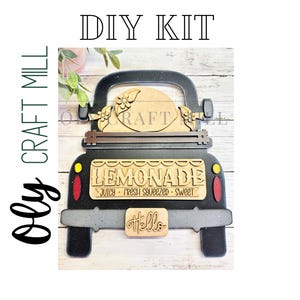 May include: DIY kit for a wooden truck-shaped sign. The sign is black and gray with a "Lemonade" sign and the words "Juicy - Fresh Squeezed - Sweet". A small sign says "Hello". The sign has a wooden floral design.