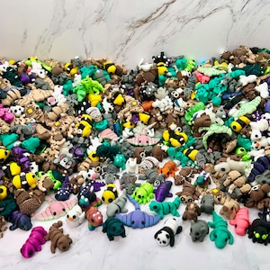 May include: A large collection of colorful, miniature animal figurines made of polymer clay. The figurines include a variety of animals, such as cats, dogs, birds, fish, and insects. The figurines are all hand-painted and have a variety of textures and details.