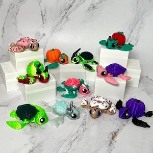 May include: A collection of ten hand-painted turtle figurines. The turtles are decorated with various themes, including a pumpkin, a donut, a rose, and an apple. The figurines are made of polymer clay and are approximately 2 inches in size.