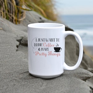 May include: White ceramic coffee mug with black text that reads "I just want to drink coffee & make pretty things". The text is surrounded by a black coffee cup with steam coming from it.