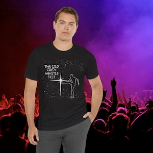 May include: Black t-shirt with a white graphic of a person kicking a star with the text "THE OLD GREY WHISTLE TEST" on the front.