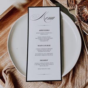 May include: A formal menu card with a black border, featuring the word "Menu" in elegant script. The menu lists appetizers, main courses, and desserts. The card is placed on a white plate, with silverware and decorative elements.