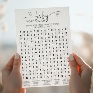 Può includere: Un biglietto bianco per il gioco di ricerca di parole per baby shower con la parola "baby" in corsivo e un design a cuore. La carta include un puzzle di ricerca di parole e un elenco di parole relative ai bambini.