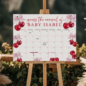May include: A white sign with a cherry theme, reading "guess the arrival of BABY ISABEL" with a calendar for January and February. The due date is marked with a red heart.