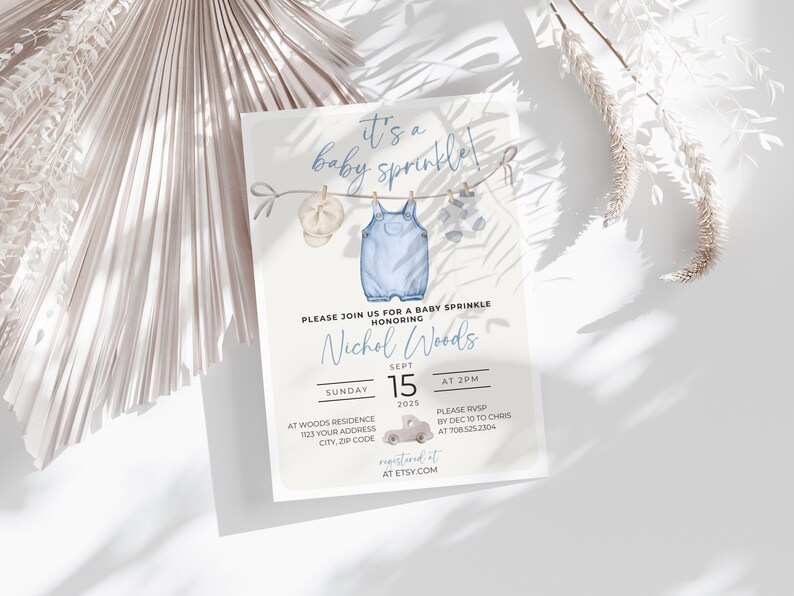 May include: A blue baby shower invitation with a watercolor illustration of a baby's outfit hanging on a clothesline. The invitation reads "It's a baby sprinkle!" and includes the name "Nichol Woods", the date "Sept 15, 2025", and the time "At 2pm".