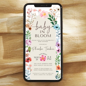 May include: A floral baby shower invitation with a watercolour design. The invitation features a pink and white flower with the text "baby in bloom" and the name "Phoebe Tonkin". The invitation also includes the date and time of the shower, as well as the address and RSVP information.